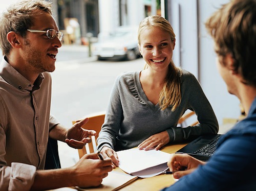 Young woman having business meeting in cafe with two men, smiling